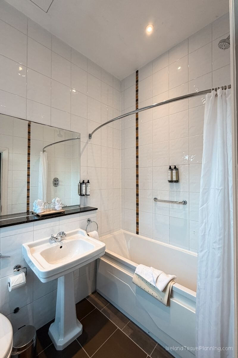 Modern bathroom with white tiles, sink, bathtub, and shower curtain