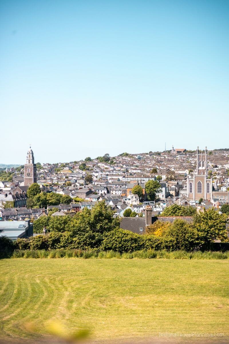 Aerial view of Cork City with buildings, trees, and a clear blue sky
