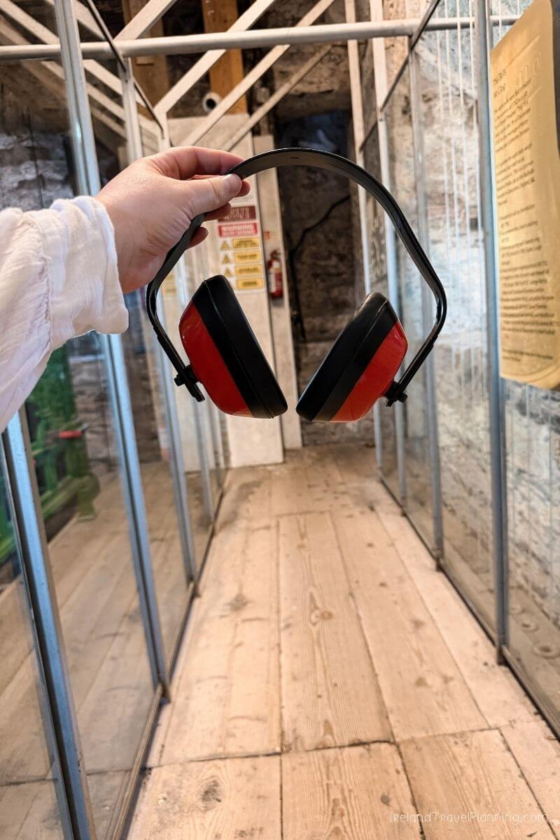 Hand holding red safety headphones in a tunnel, Cork City