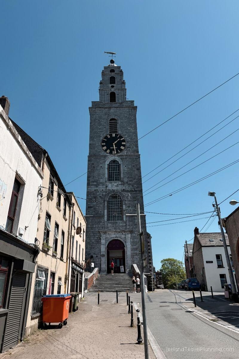 Tall stone clock tower with steps leading to entrance in Cork City