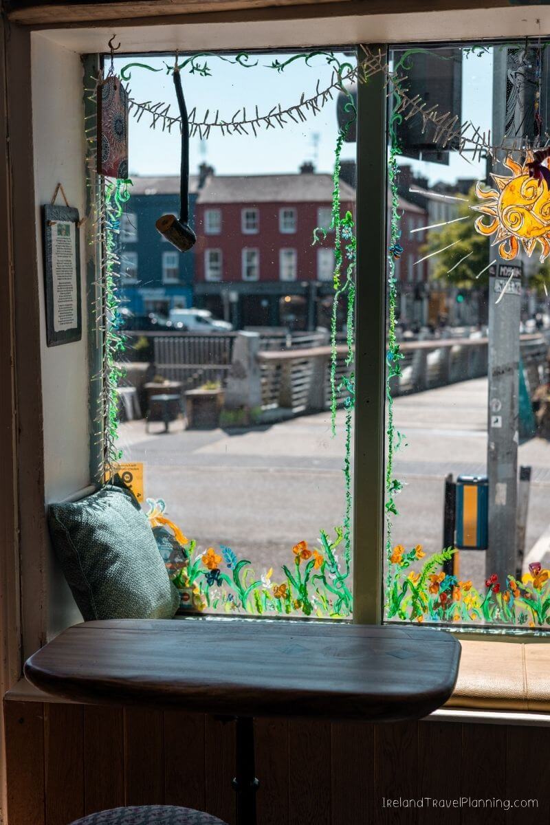 Cozy window seat with a table overlooking a street scene in Cork City, Ireland.