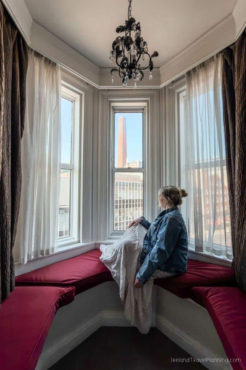 Woman in denim jacket sitting on a window seat, overlooking the city skyline