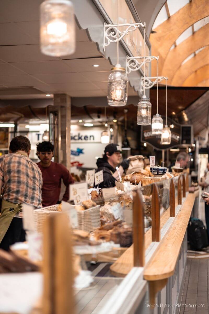Bakery counter with various bread and pastries displayed, customers in foreground