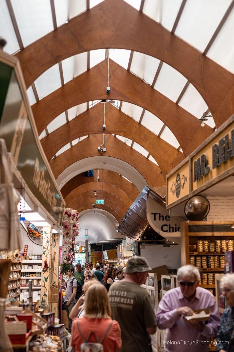 Busy Cork City market with arched ceiling and shop signs