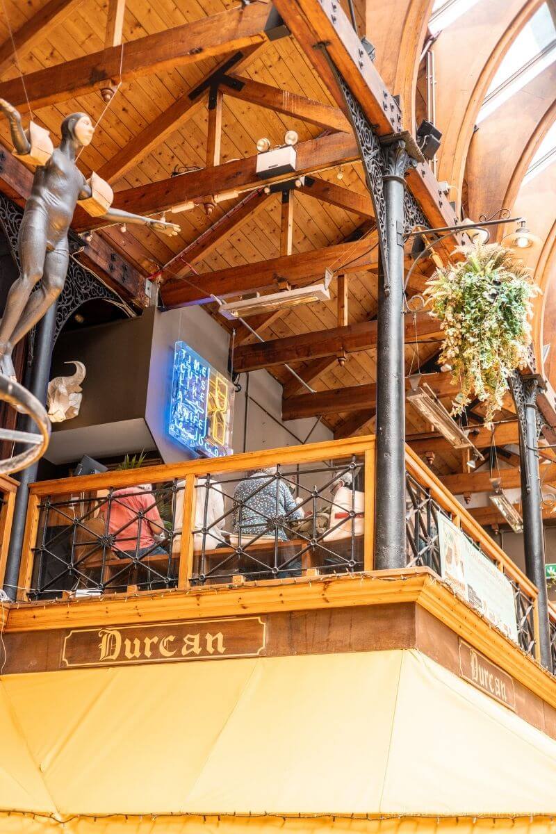 The English Market in Cork City, featuring wooden beams and a hanging plant.