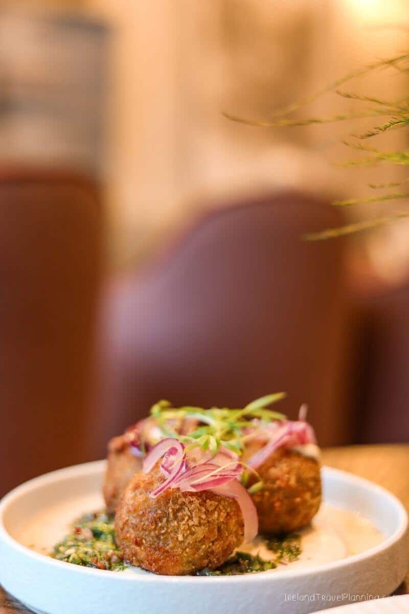 Plate of seasoned potato croquettes with green garnish on a wooden table