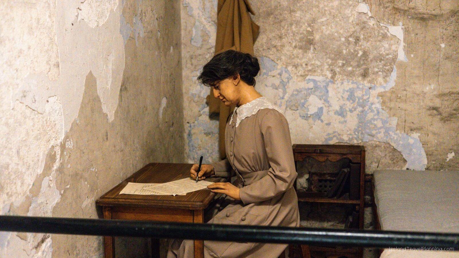 Recreation of a woman writing at a desk in a historical Cork City prison cell.