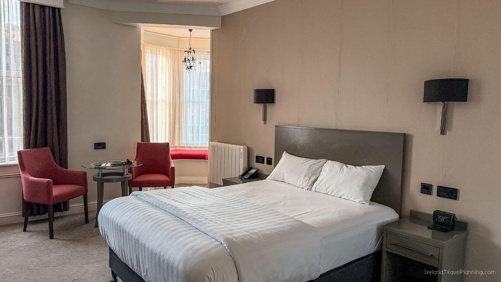 Elegant hotel room with bed, chairs, and window view in Cork City