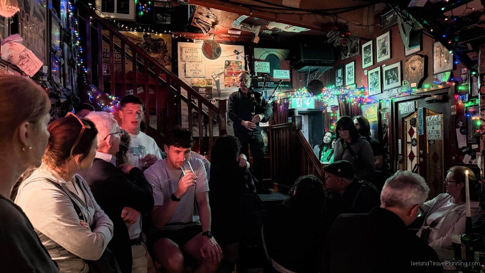 Bagpiper performing in a lively Cork City pub with patrons enjoying drinks