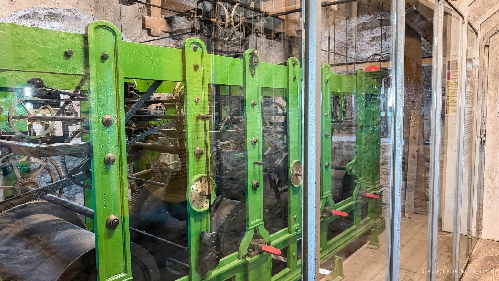 Green machinery with metal gears and parts inside a glass display case
