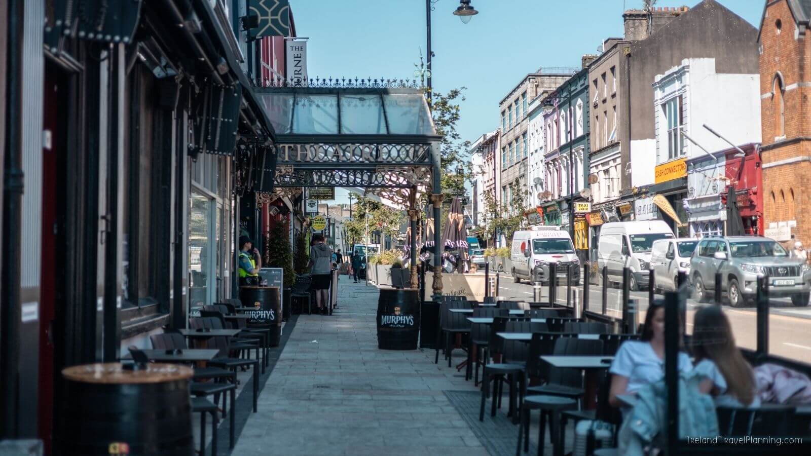 Outdoor cafe with tables and umbrellas on Cork City sidewalk
