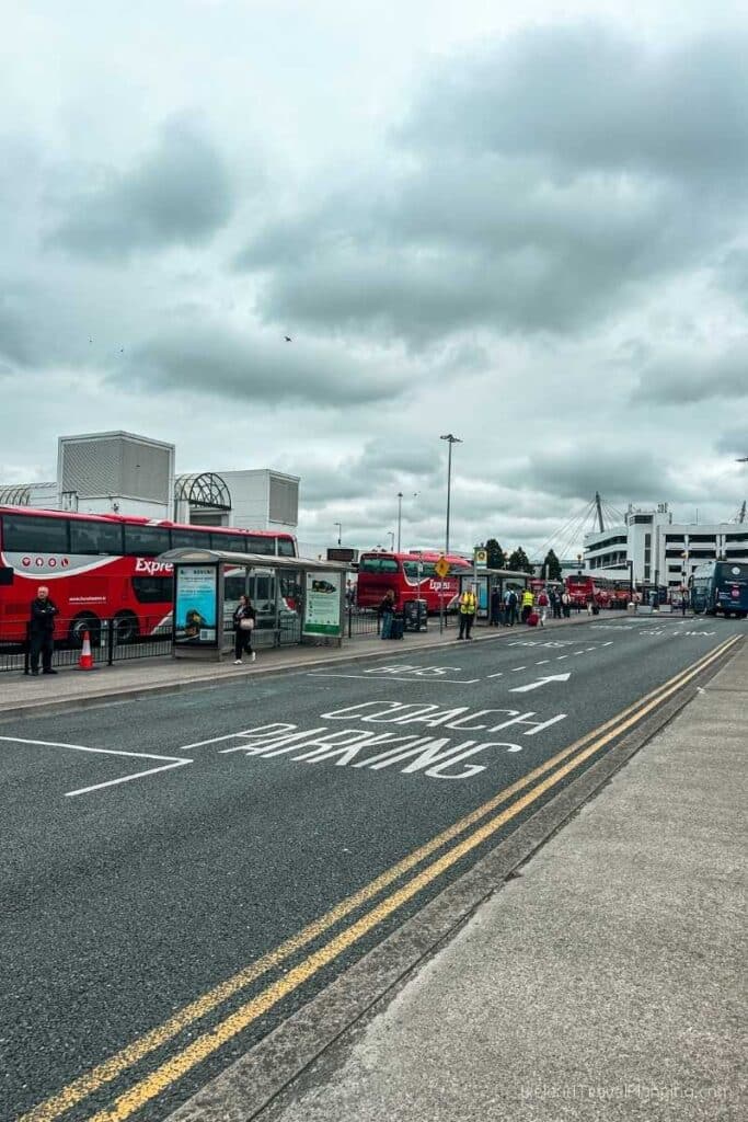 Red National Express coaches at a bus station with "Coach Parking" painted on the road.