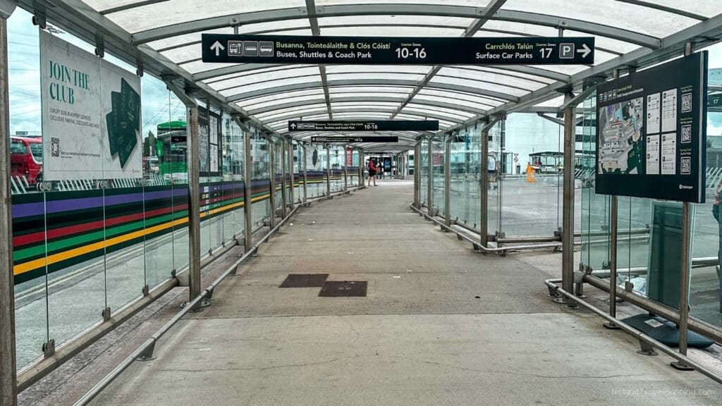Covered walkway at Dublin Airport with signs for bus, shuttle, and coach parking.