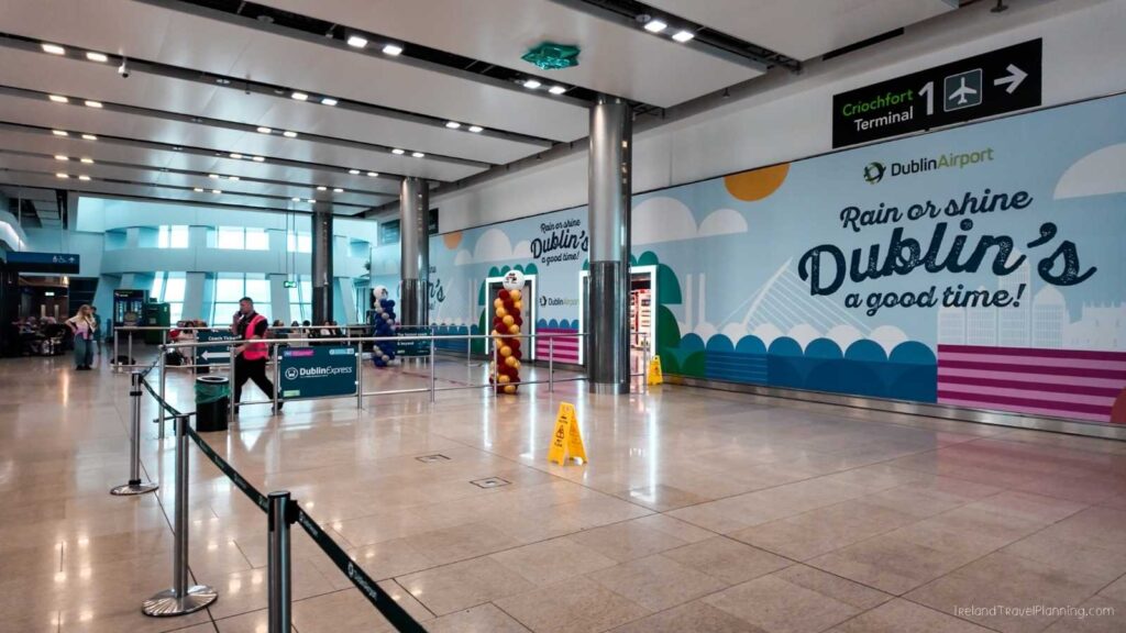 Dublin Airport Terminal 1 arrivals hall with Dublin Express signage and promotional banner.