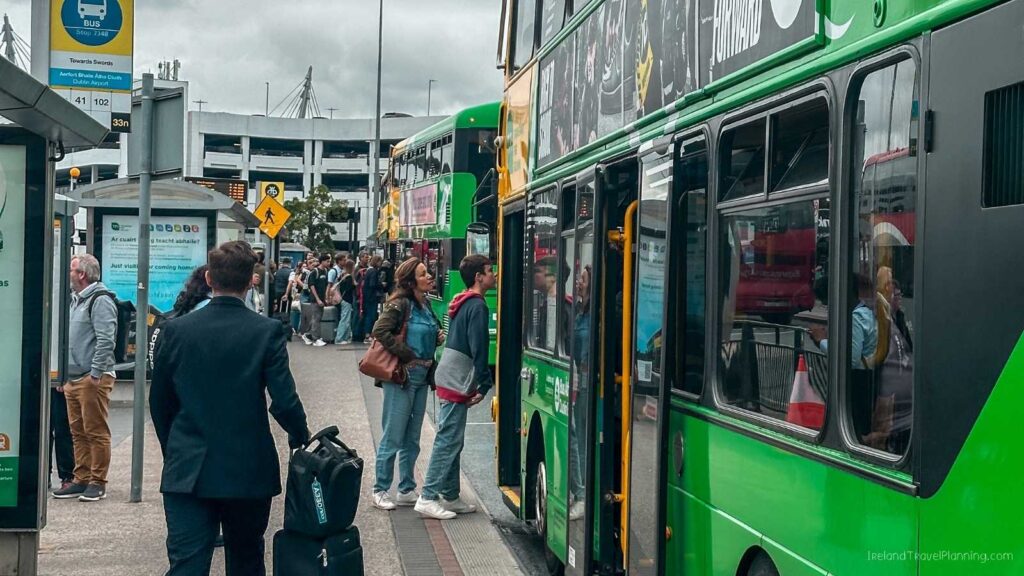 People boarding a green double-decker bus at a Dublin bus stop.