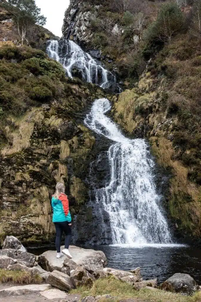 Woman in blue jacket admiring Powerscourt Waterfall, Ireland