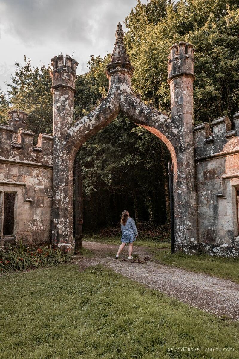 Woman walking through a gothic stone archway at a hidden gem in Ireland.