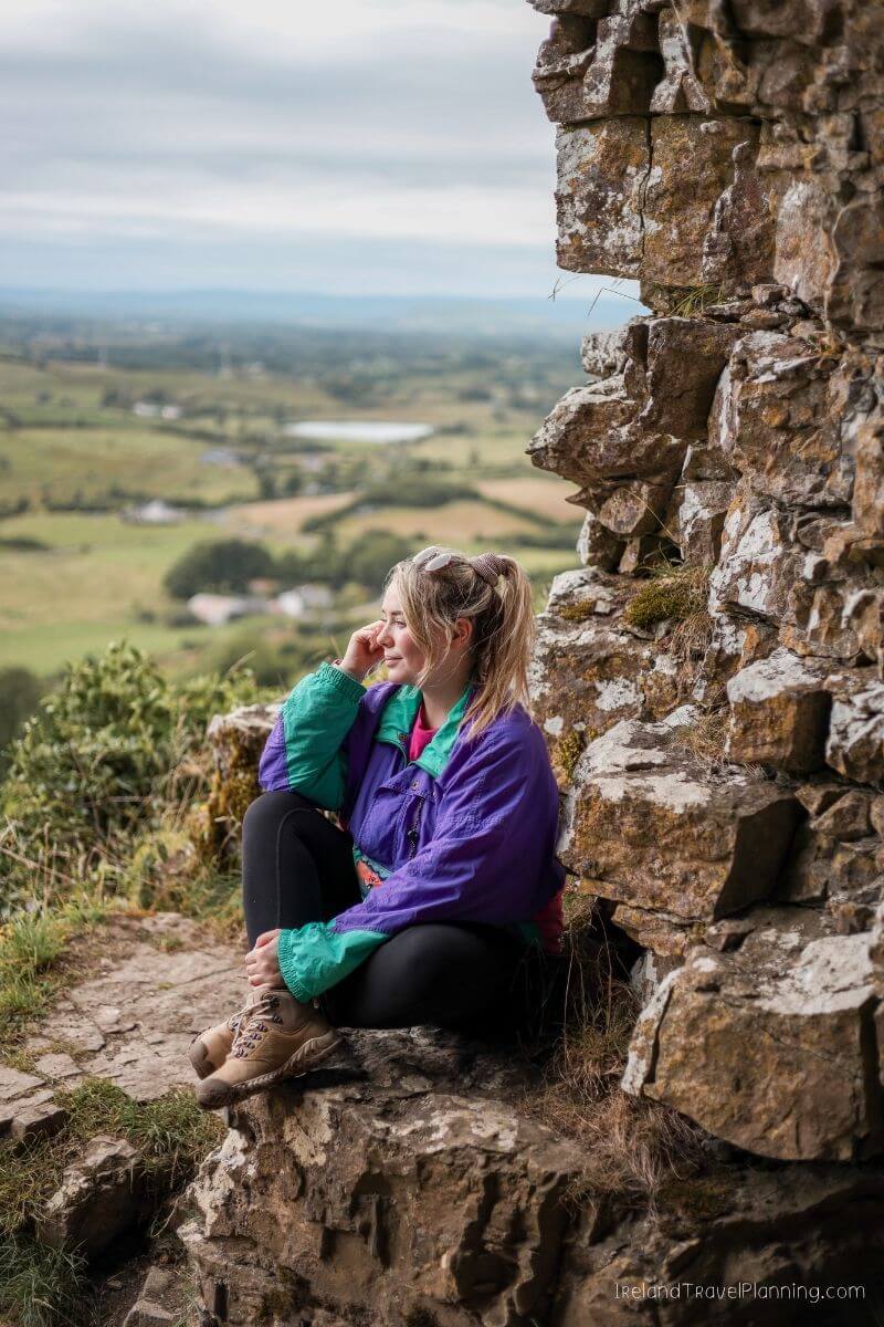 Woman in purple jacket overlooking Irish countryside from ancient ruins