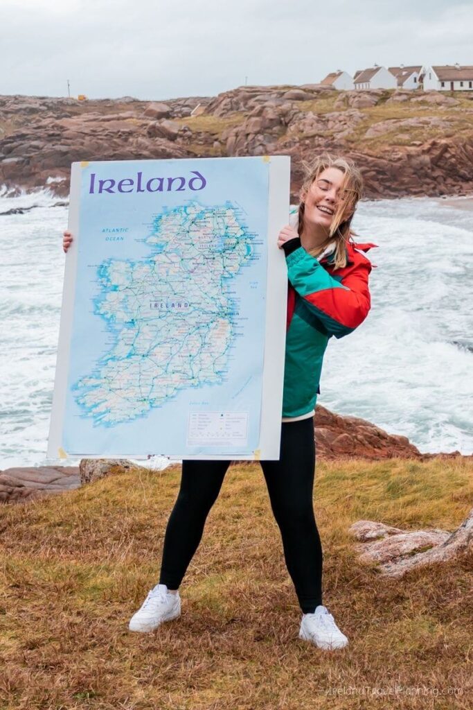 Woman holding an Ireland map on a cliff overlooking the Atlantic Ocean