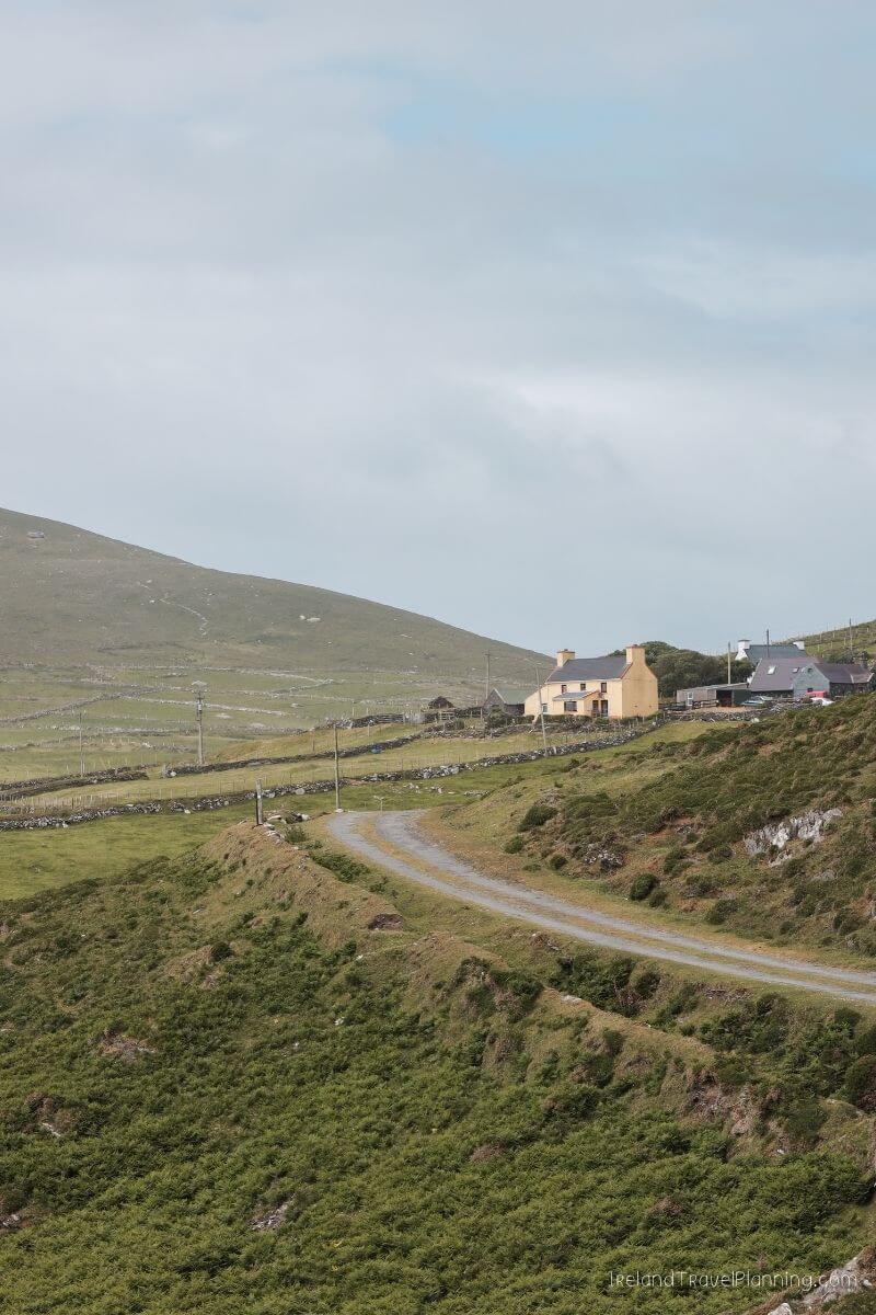 Yellow Irish cottage and stone walls on a green hillside, a hidden gem