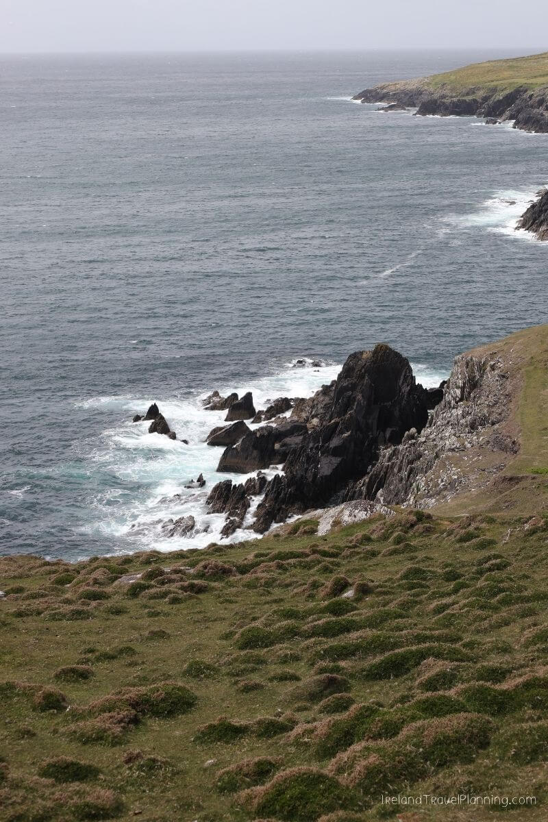Rugged Irish coastline with rocky outcrops and waves crashing on the shore.