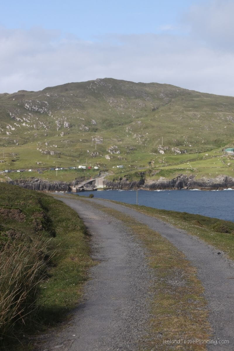Hidden gem gravel road near water in Ireland with a mountain in the background