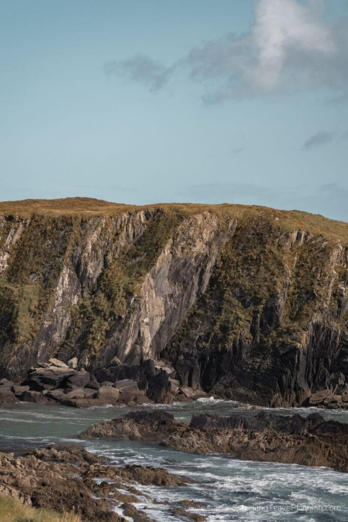 Rugged Irish coastline with dramatic cliffs and waves crashing on rocks.