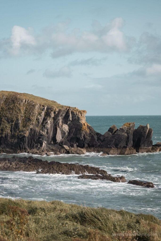 Rugged Irish coastline with dramatic cliffs and waves crashing on rocks.