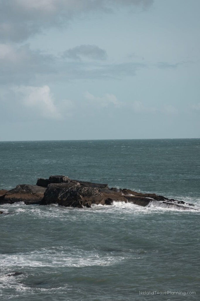 Rugged rock formation in the Atlantic Ocean, Ireland, with waves crashing.