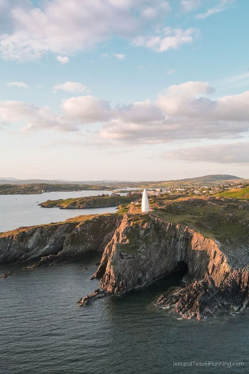 White lighthouse on a rocky cliff overlooking the sea in Ireland