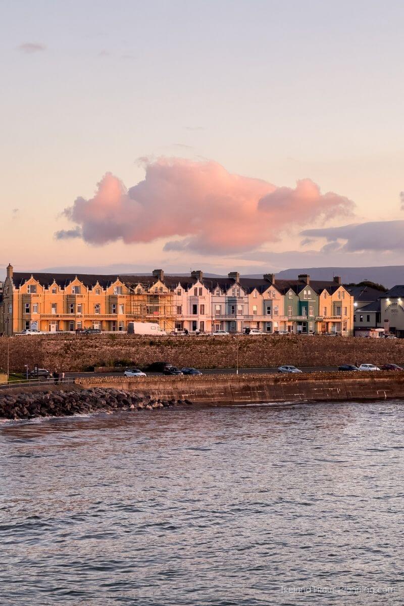 Colorful row of terraced houses on a waterfront in Ireland at sunset.