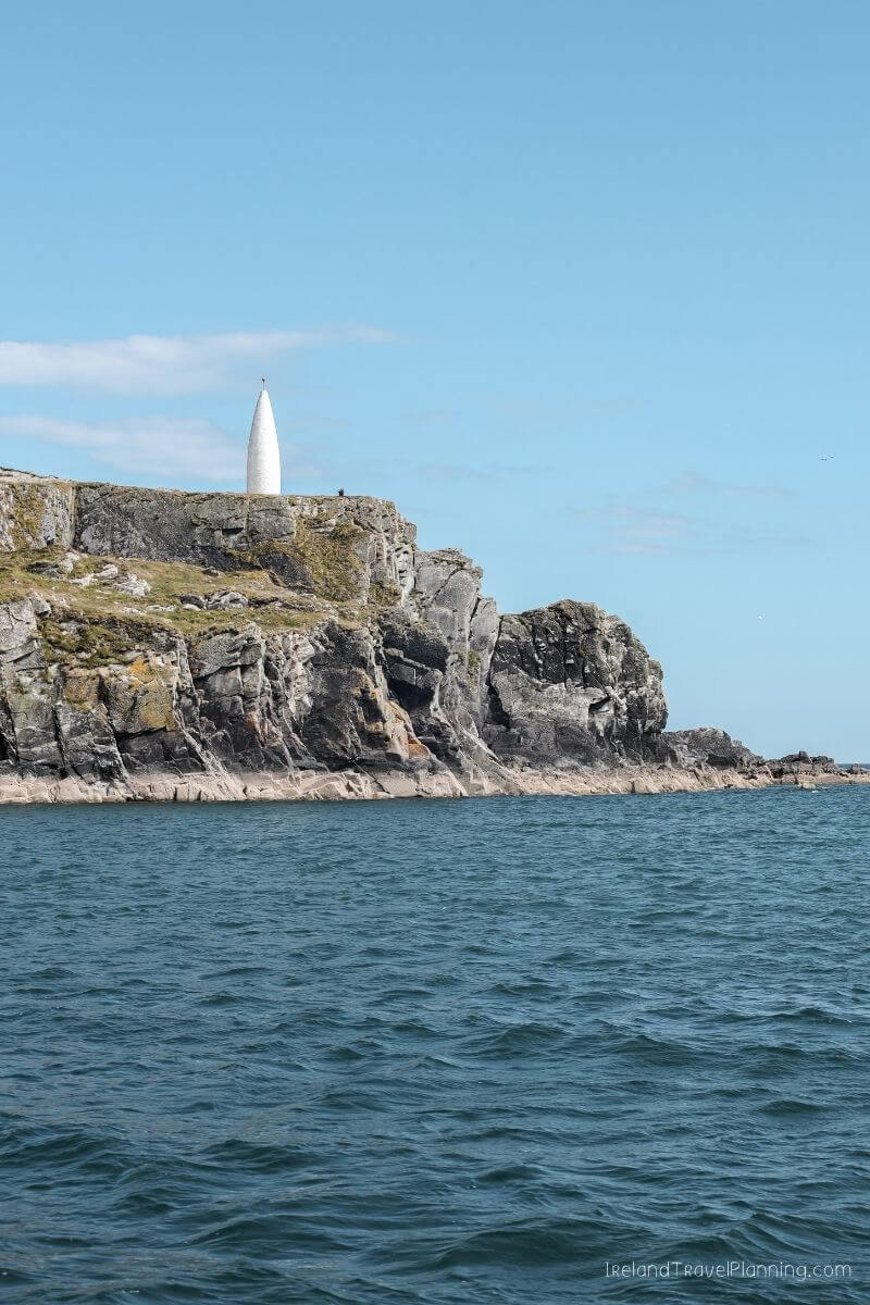 Coastal Ireland: White spire on rocky cliff overlooking the sea