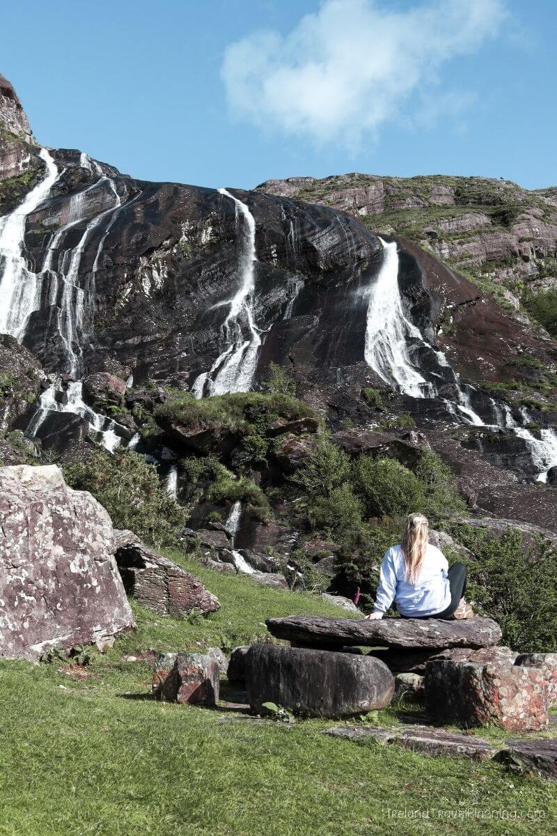 Woman sitting on rocks near waterfall in Ireland