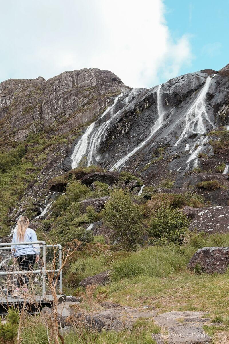 Woman admires Ireland's stunning Glenariff Waterfall, a hidden gem.