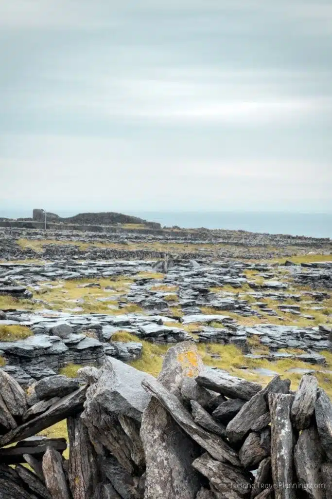 Rocky landscape with stone walls and green grass under a cloudy sky