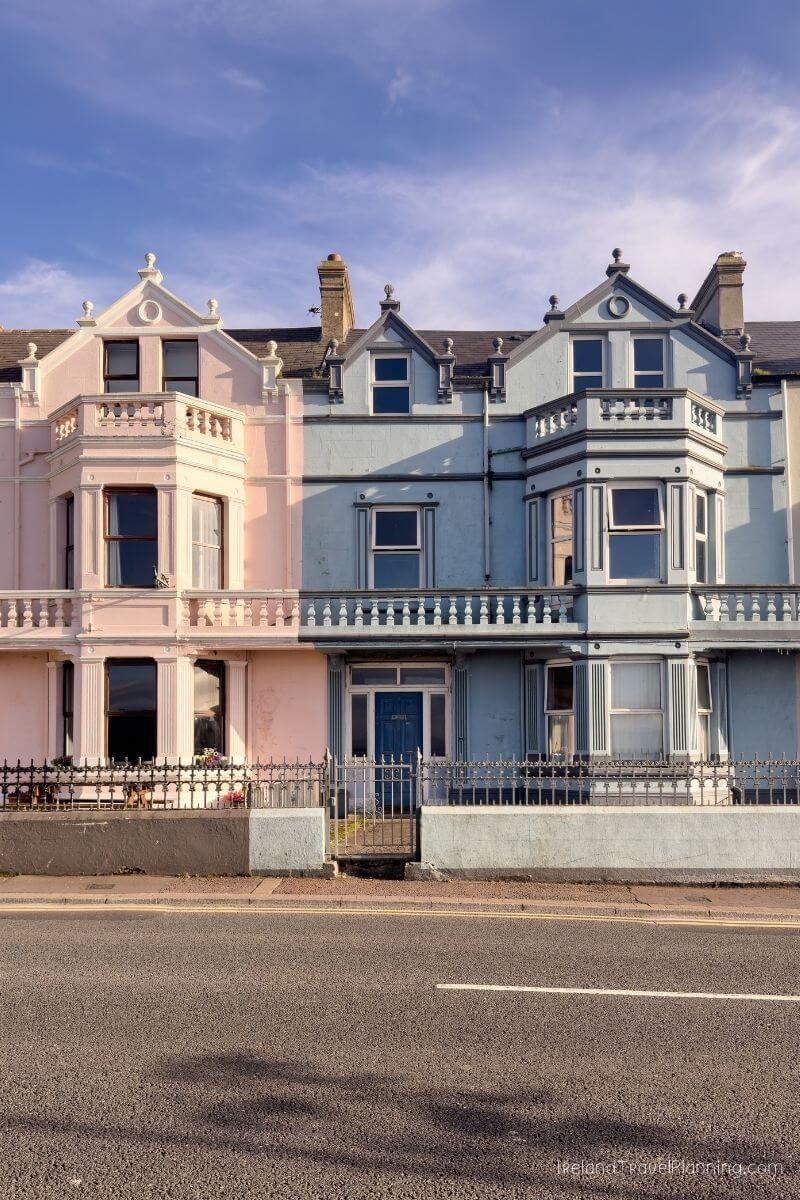 Pastel pink and blue Victorian houses with ornate details on a sunny day.