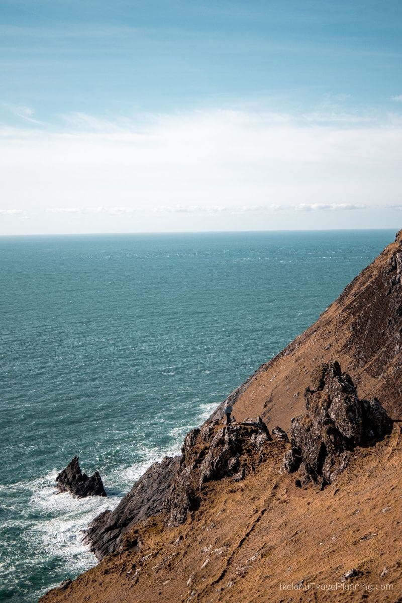 Man on rugged cliff overlooking the sea in Ireland