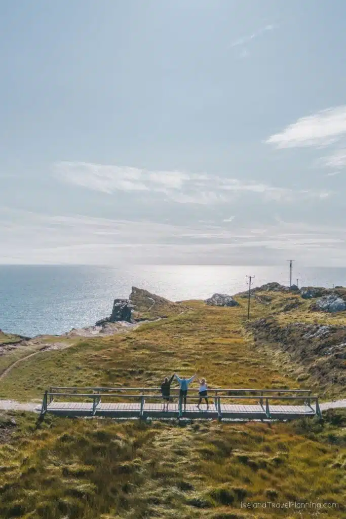 Three friends on a wooden bridge overlooking the sea in Ireland
