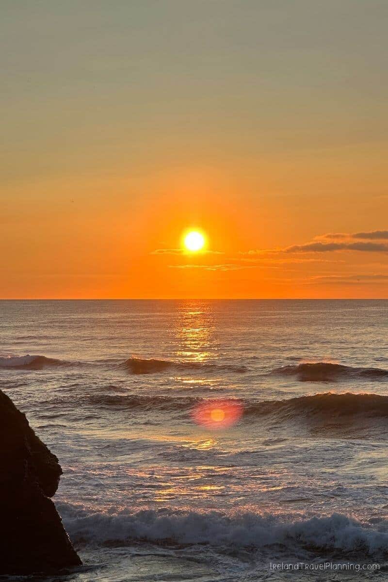 Sunset over the ocean with waves crashing on the shore, Ireland Travel Planning