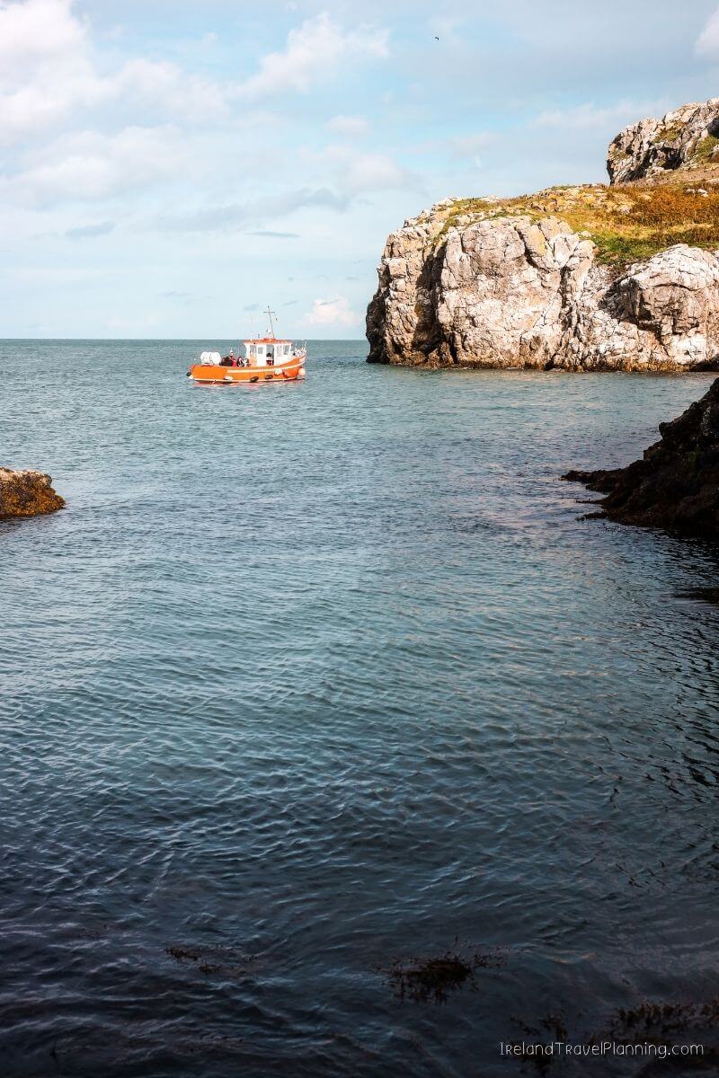 Orange boat sails near rocky cliffs in Ireland