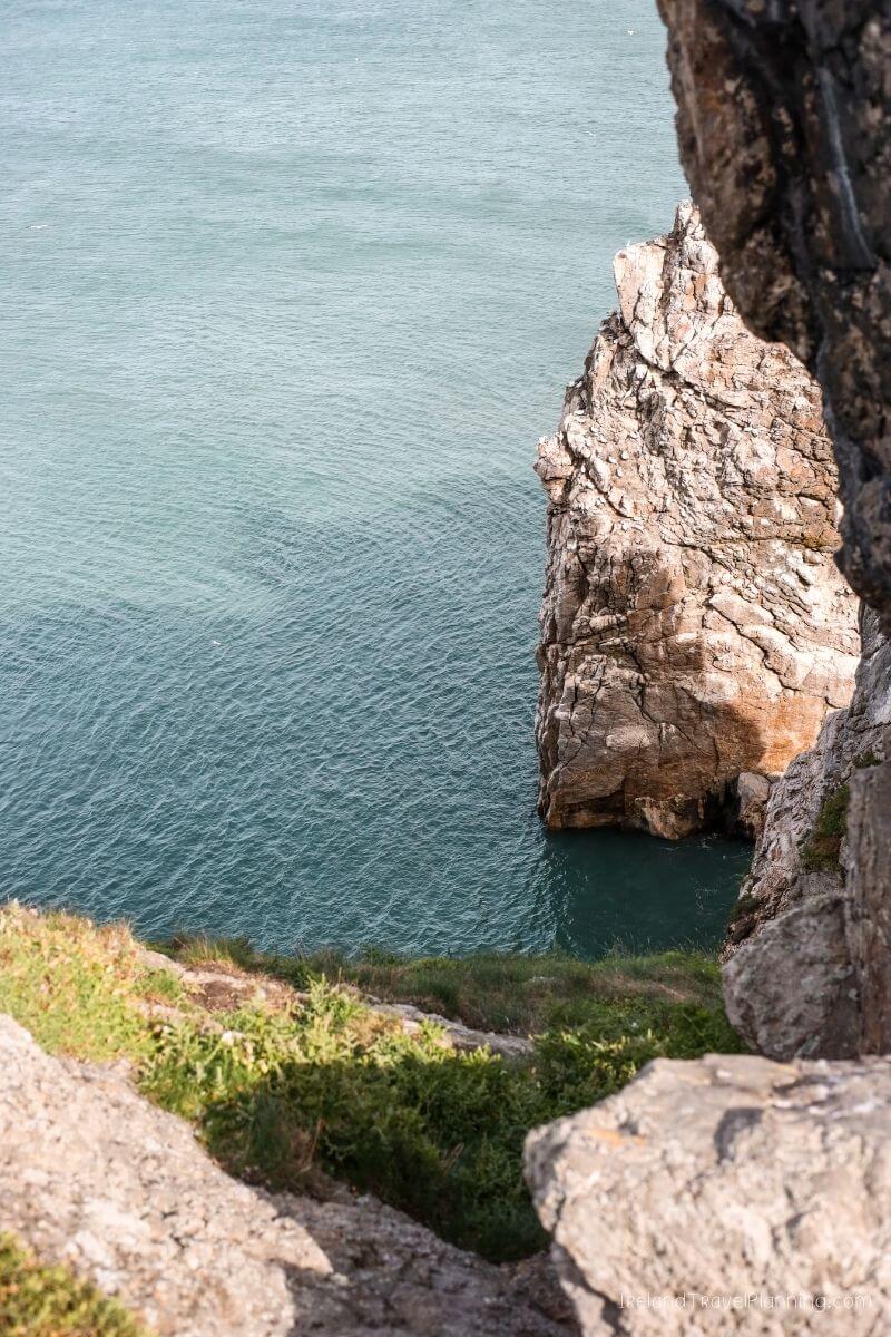 Rugged Irish coastline with dramatic sea cliffs and green vegetation.