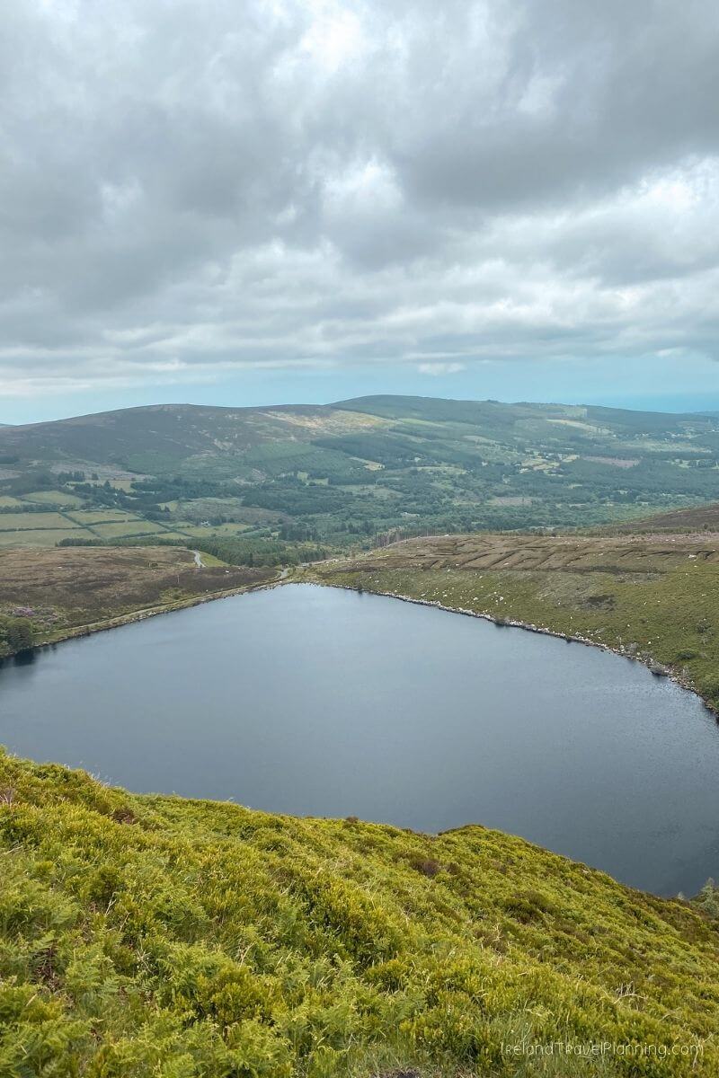 Serene lake nestled in rolling green hills of Ireland, a hidden gem.