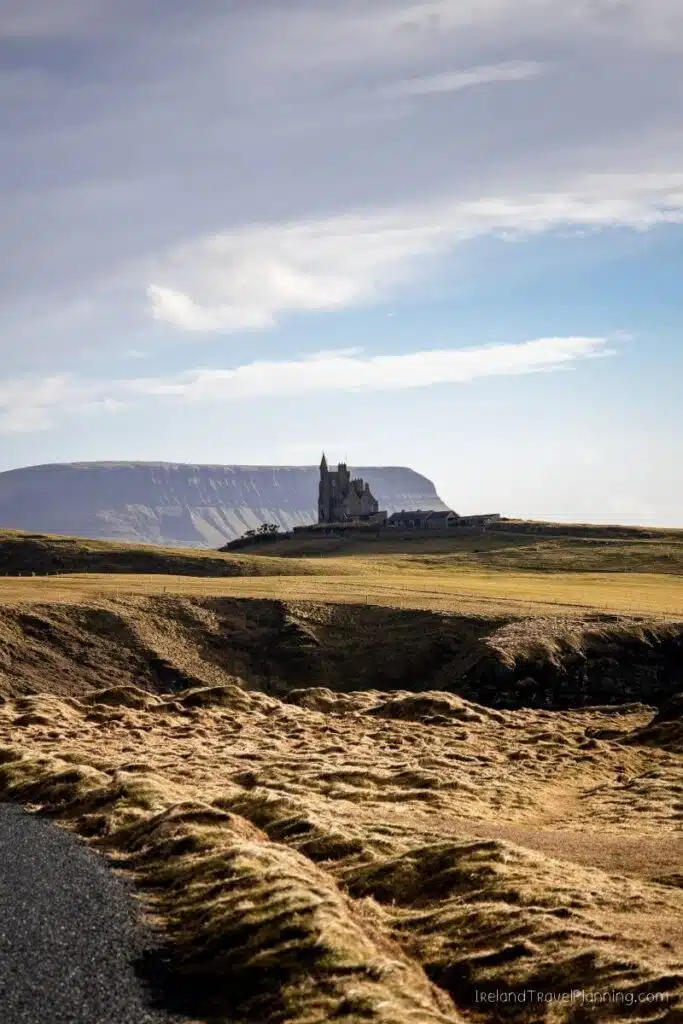 Castle on a cliff overlooking a vast, open field under a cloudy sky