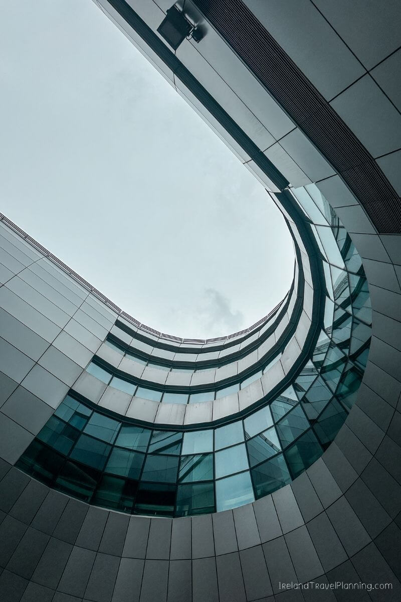 Modern architectural detail: curved glass facade reflecting a cloudy sky