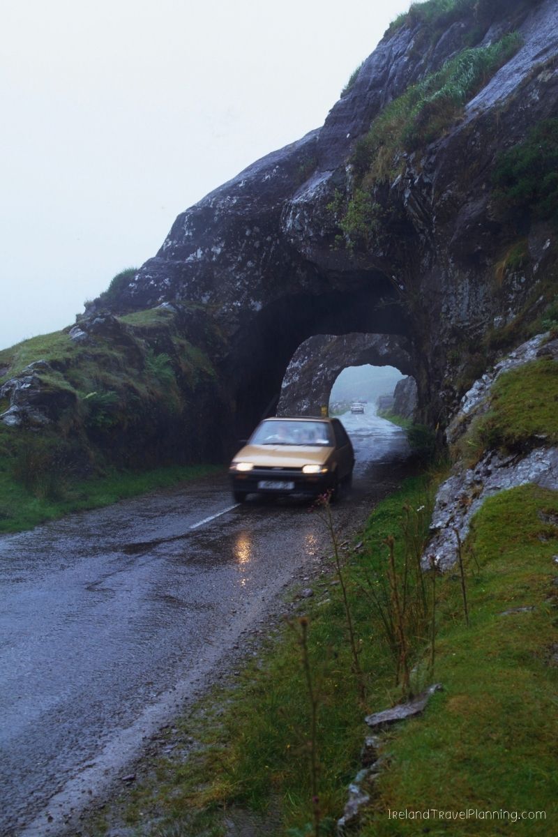 Car driving through a rocky tunnel on a wet Irish road