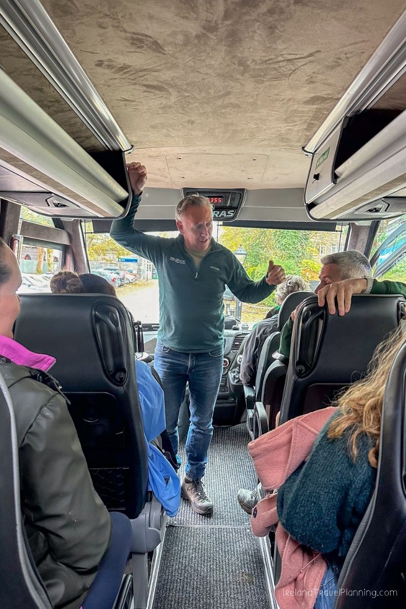 Tour guide addresses passengers on a bus in Ireland, discussing car rental options.