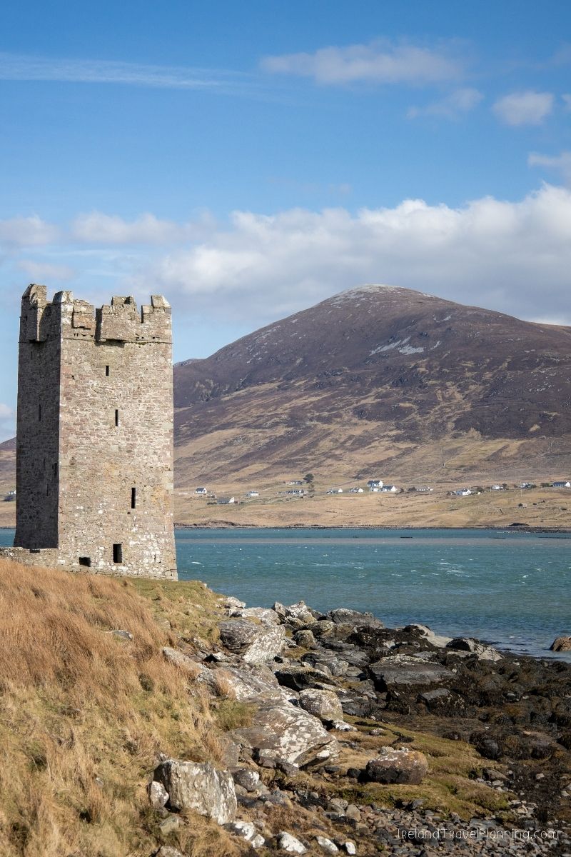 Kishkeam Castle, Ireland, with a mountain and bay in the background.