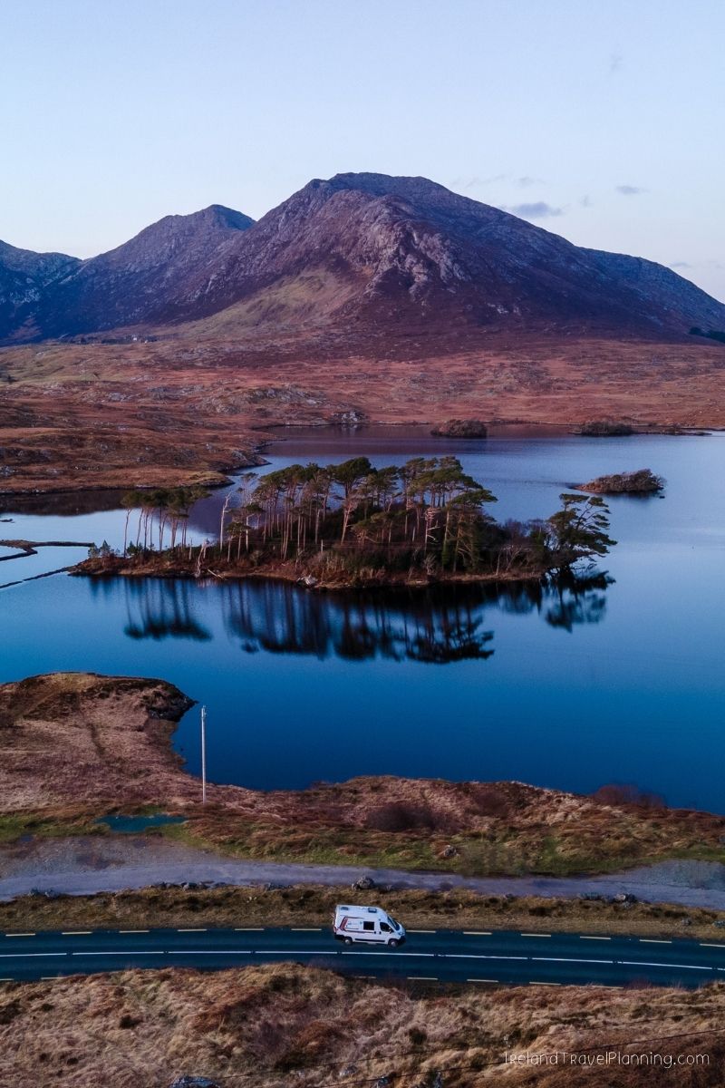 Van on a road in Connemara, Ireland, with a lake and mountains