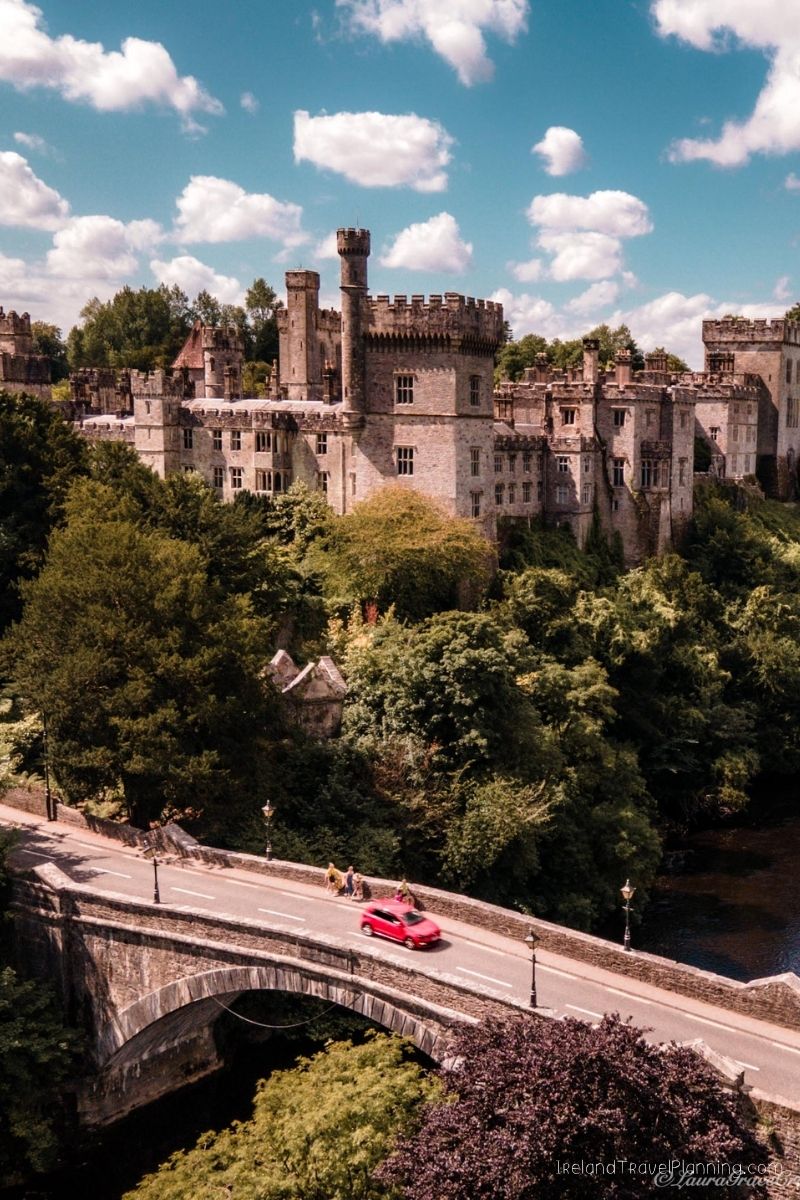 Red car crossing a bridge towards a castle in Ireland