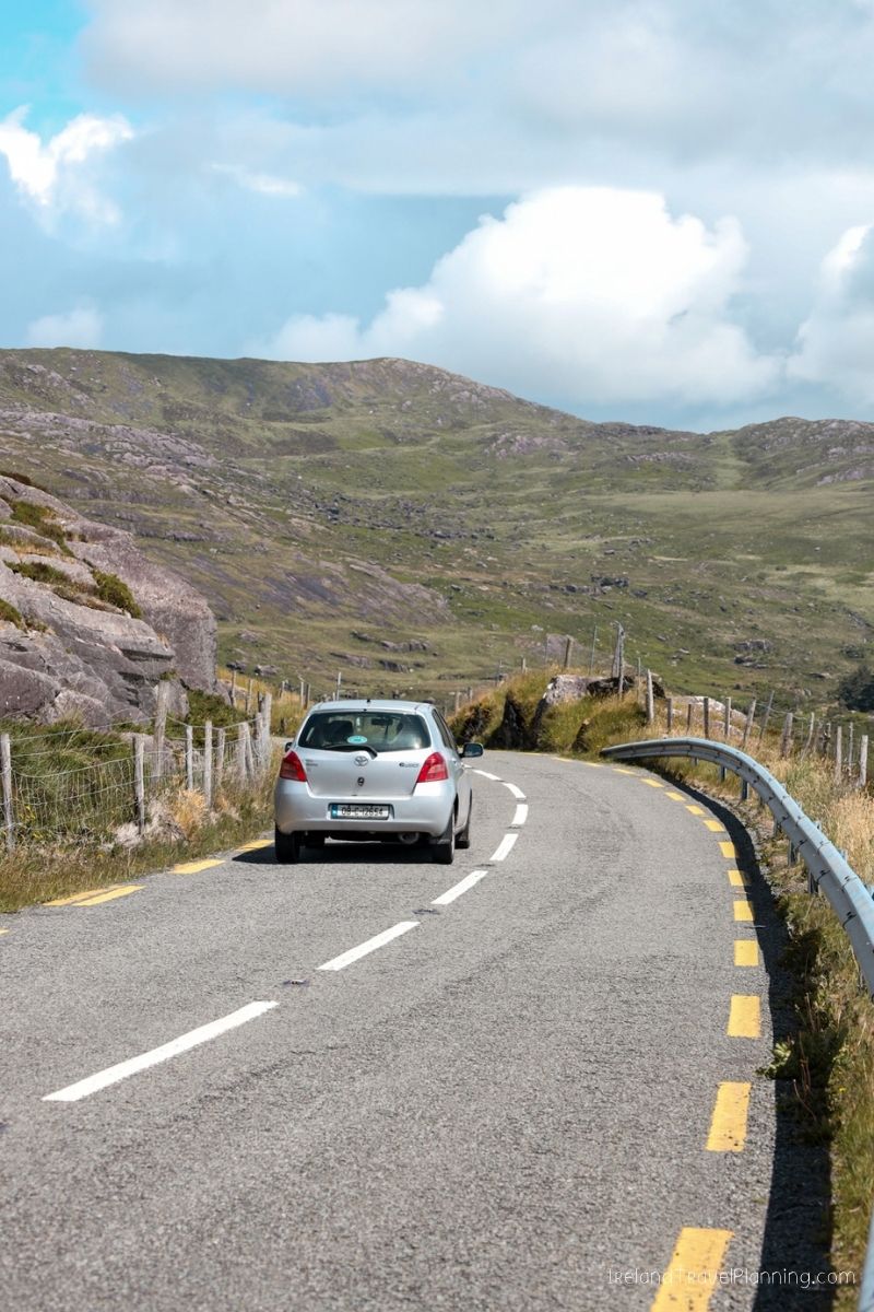 Silver car driving on a winding road through the Irish countryside